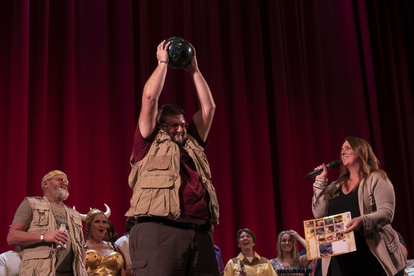 Winner holding a bowling ball prize on stage