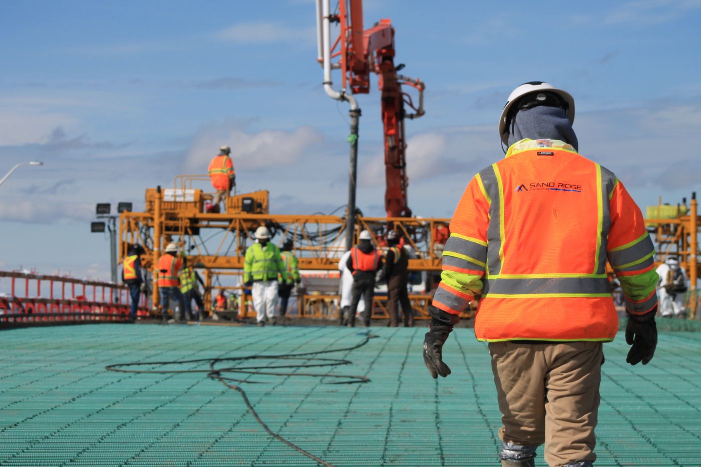Crew member walking across a bridge deck during a concrete pour, Sand Ridge Constructors